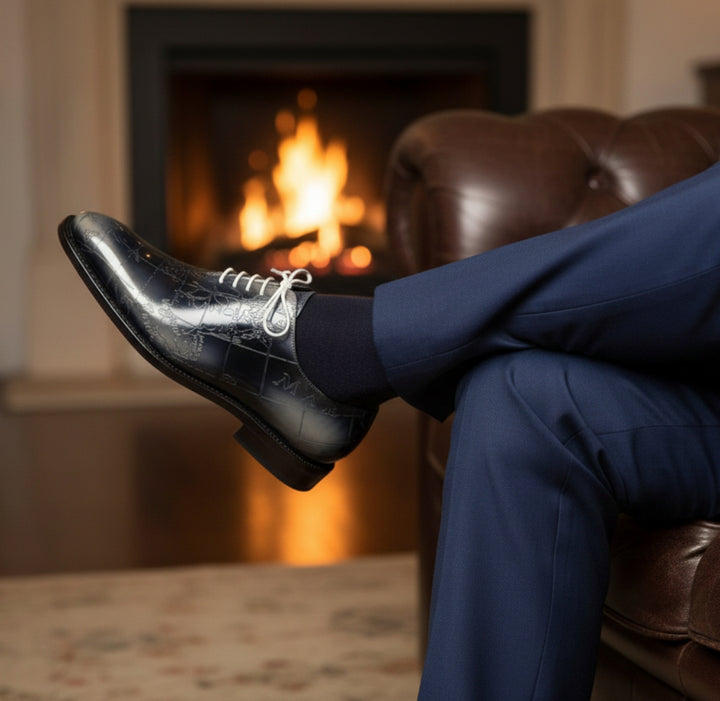 Person wearing MERRIMIUM black shoes and blue pants sitting in a chair with a fireplace in the background