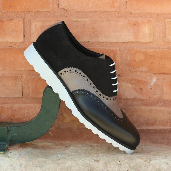 Black and brown shoe with white sole on a brick background