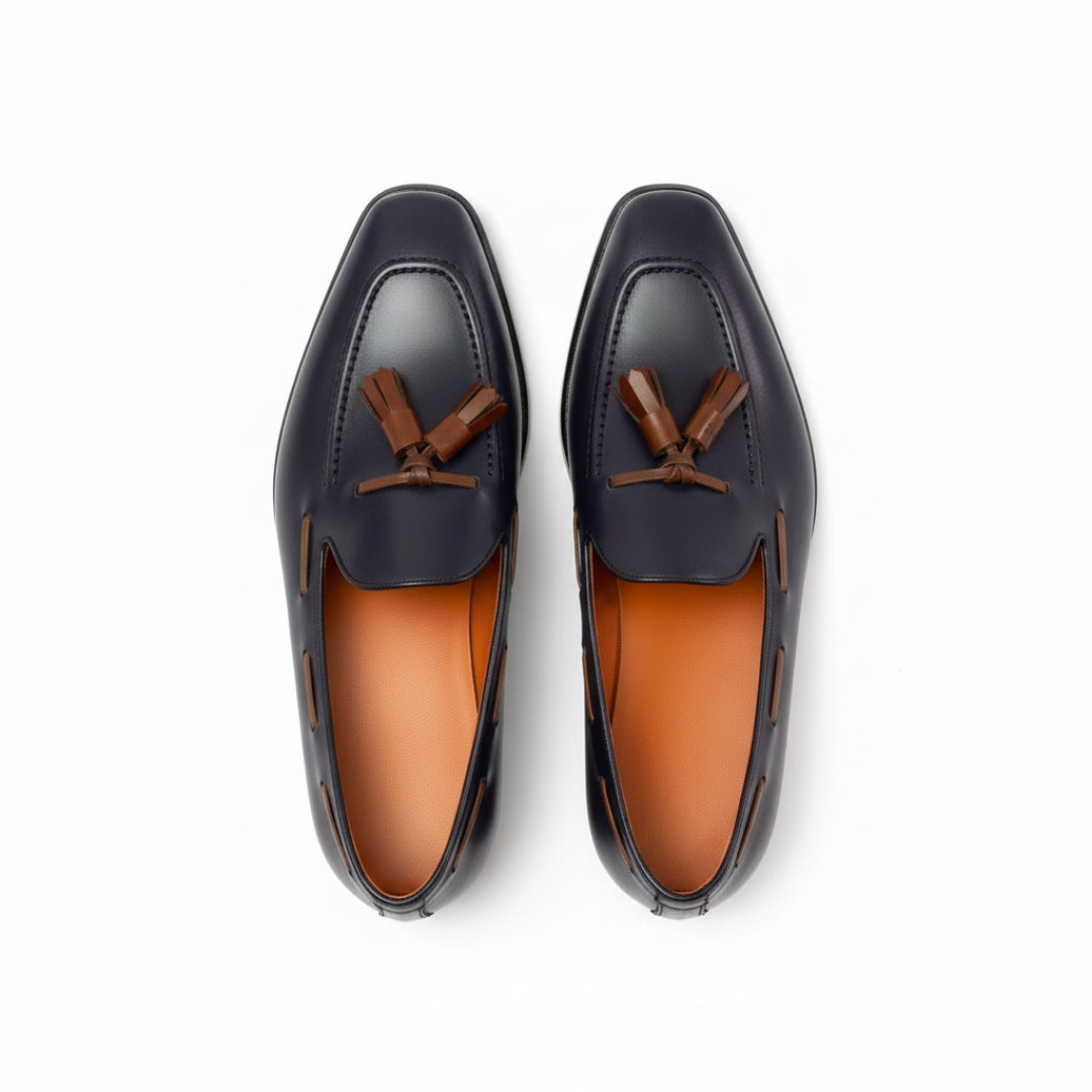 Pair of black MERRIMIUM loafers with brown accents on a white background