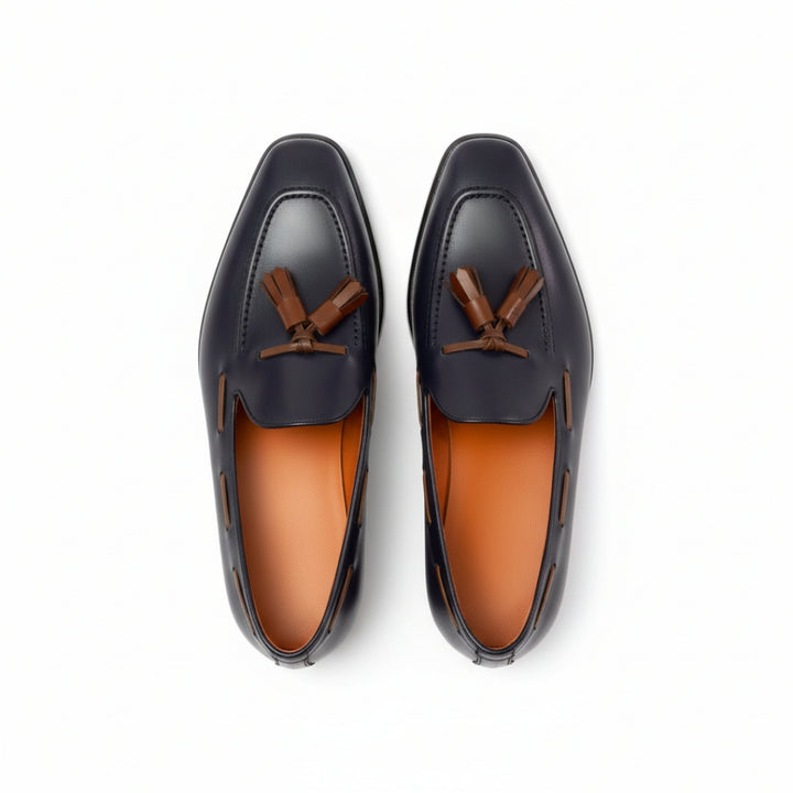 Pair of black MERRIMIUM loafers with brown accents on a white background