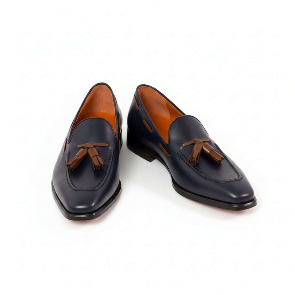 Pair of black MERRIMIUM loafers with brown tassels on a white background