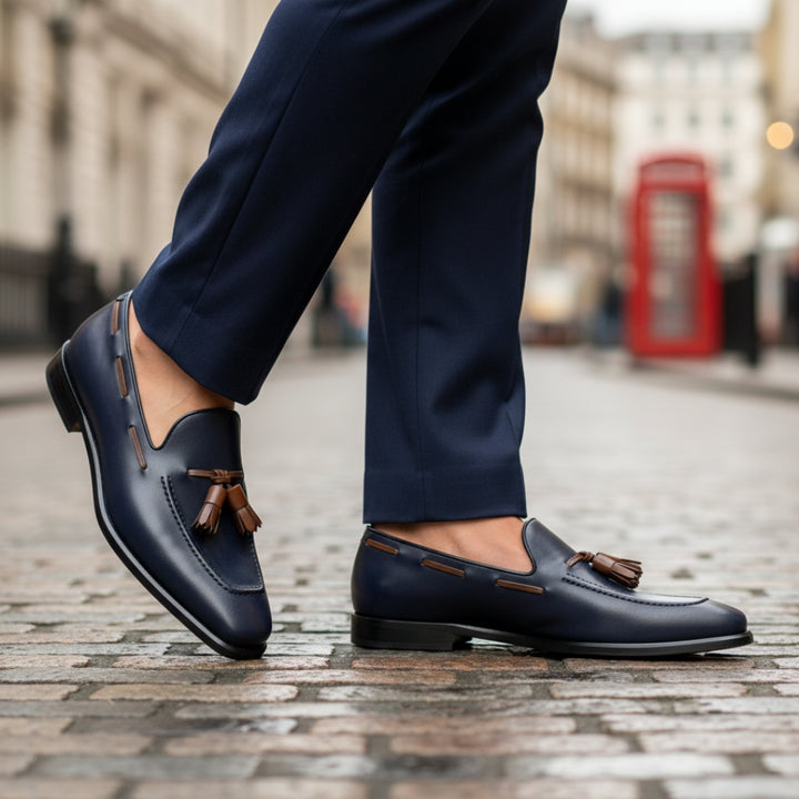 Navy MERRIMIUM loafers with brown tassels worn on a city street.