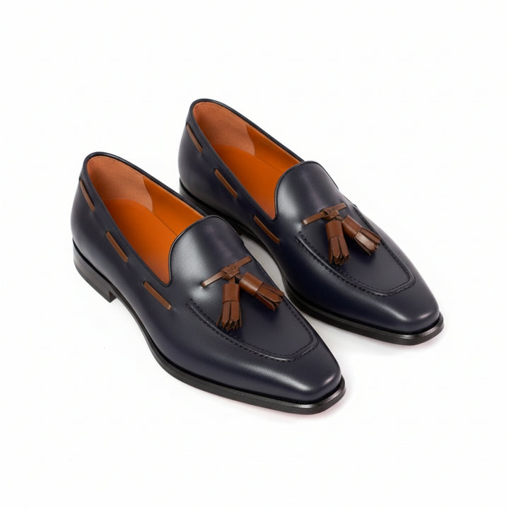 Pair of navy MERRIMIUM loafers with brown tassels on a white background