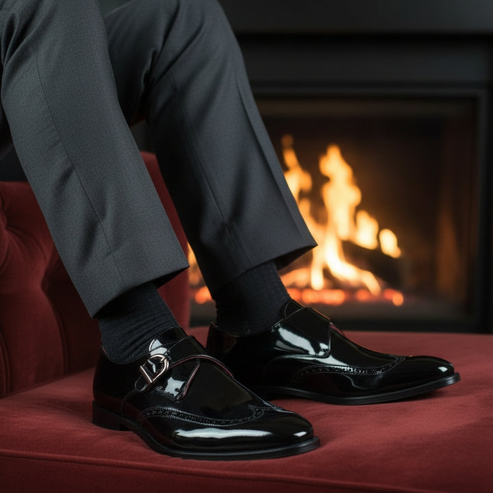 Person wearing black MERRIMIUM shoes and socks sitting on a red couch with a fireplace in the background